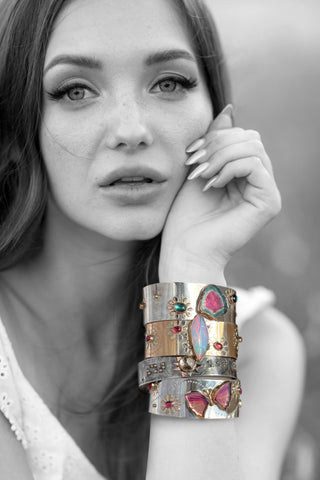 stack of bright gemstone cuff bracelets on model