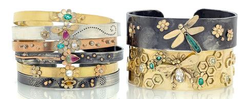 Stacks of thin cuff bracelets in solid gold and sterling silver with gemstones and diamonds on a white background