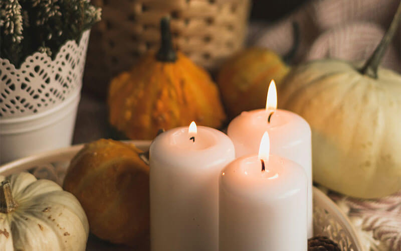 3 column candles surrounded by winter squashes, pine cones and heather.
