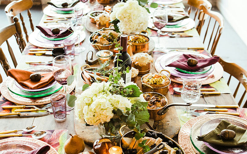A table spread with places set ready for guests. The table is filled with pans and dishes of food.