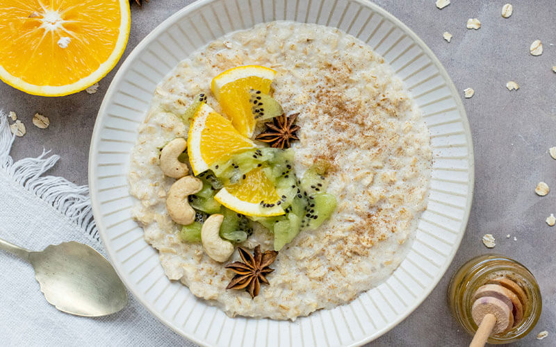 A high fibre bowl of oatmeal with kiwi, lemon, nuts and star anise.