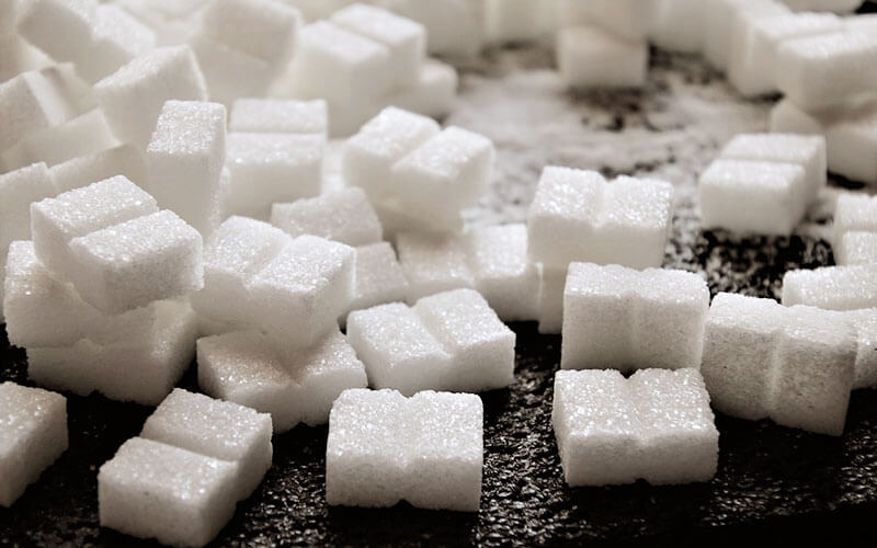 A pile of sugar cubes on a dark wooden table.