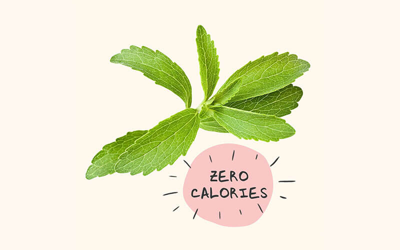 A cut out image of a cluster of stevia leaves on a cream background with a pink circle with the text "zero calories".