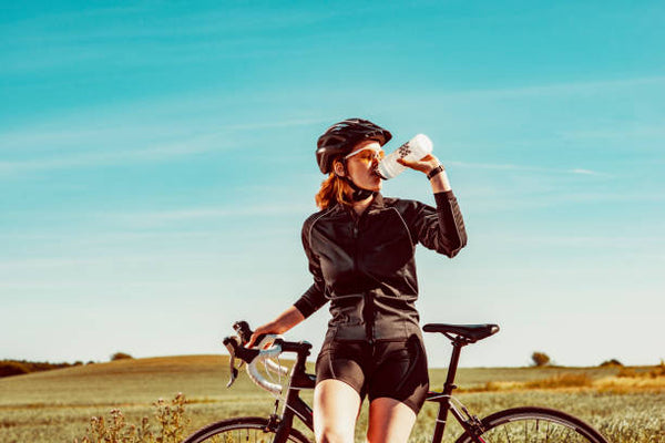 Ciclista che gusta una bevanda energetica durante una pedalata in bicicletta.