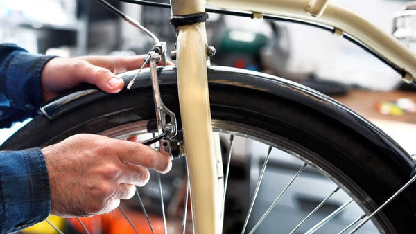 Immagine che mostra il processo di regolazione dei freni nel regolamento della bicicletta, mostrando un primo piano delle mani di un meccanico che lavora sui freni della bicicletta, sottolineando l'importanza di questo passaggio per la sicurezza.