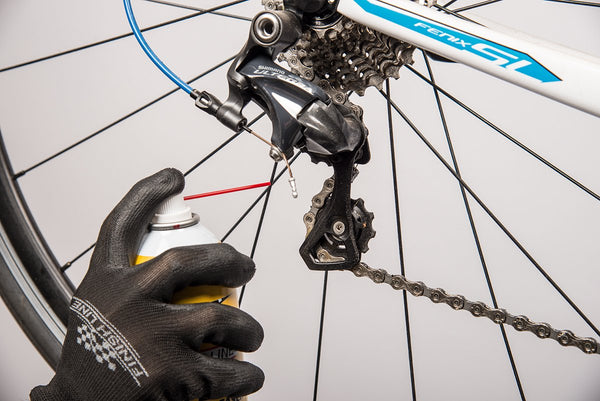 Image montrant le processus de lubrification d'une chaîne de vélo et l'ajustement du dérailleur, comme dernières étapes d'un entretien de vélo, avec des outils et du lubrifiant en évidence, mettant l'accent sur l'importance de ces tâches pour des performances optimales du vélo.