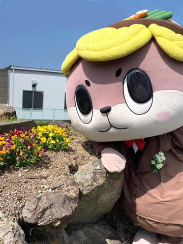 The mascot Shinjo-kun stands up close to the camera, leaning against a rock. For an otter wearing an earthen-wear bowl, he's pretty darn cool.