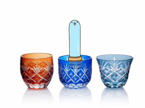 Tarutaru shoots his slime-like head up in order to view out of a blue Satsuma Kiriko glass. There are two other Satsuma Kiriko glasses beside him, in red and light blue. All the cups have beautiful, intricate patterns carved into them, and are nearly transparant.