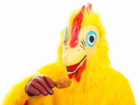 A close-up photo of a chicken mascot biting into a plastic chicken leg.