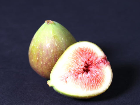 A picture of a juicy, cut fig. The white/green of it's outer flesh shines deliciously against the red of it's inner meat.