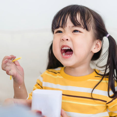 A screaming Japanese child holding what appears to be a piece of uncooked pasta