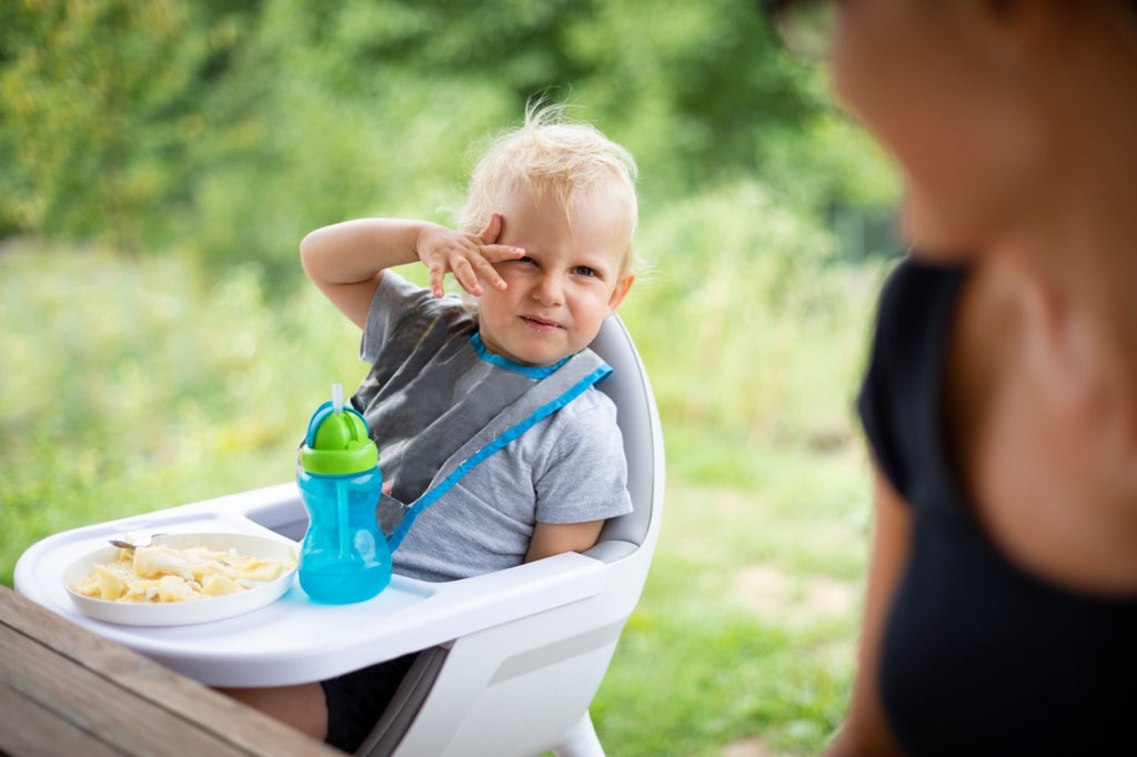 Offended and fussy little child boy during eating outdoor