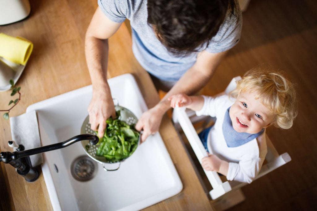 Young father with a toddler boy cooking. A man with his son making vegetable salad. Top view.