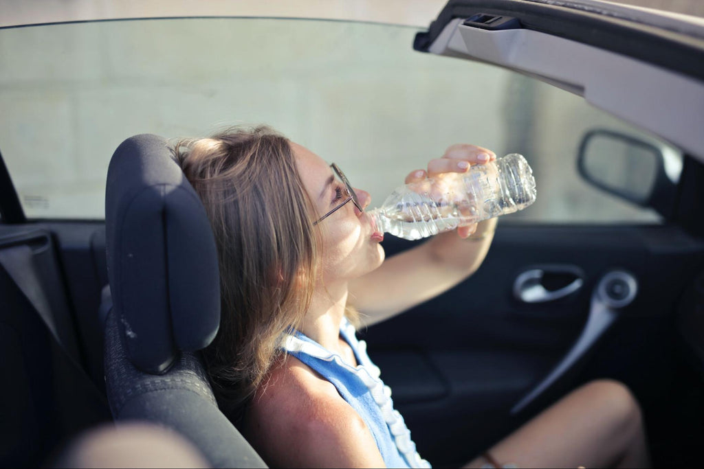 A woman drinking from a plastic bottle of water