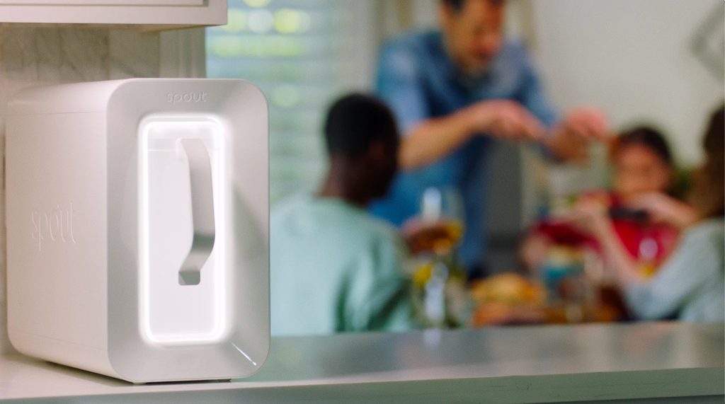 A sleek white box with curved corners and a handle, family in the background out of focus drinking