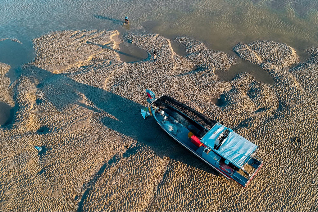 A boat sitting on the sand in shallow water