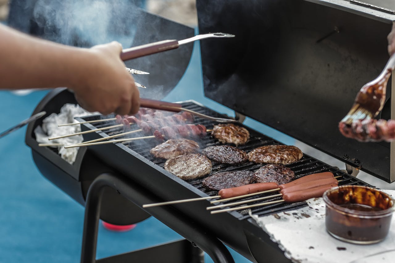 A person grilling burgers and hot dogs