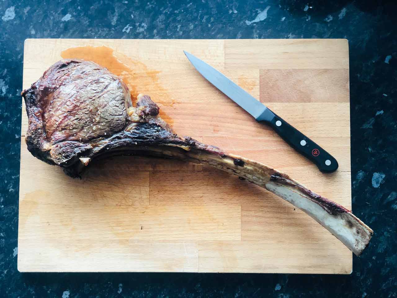A tomahawk steak resting on a cutting board