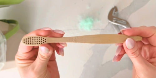 Women holding bamboo toothbrush with all the bristles removed. Ready to be composted.