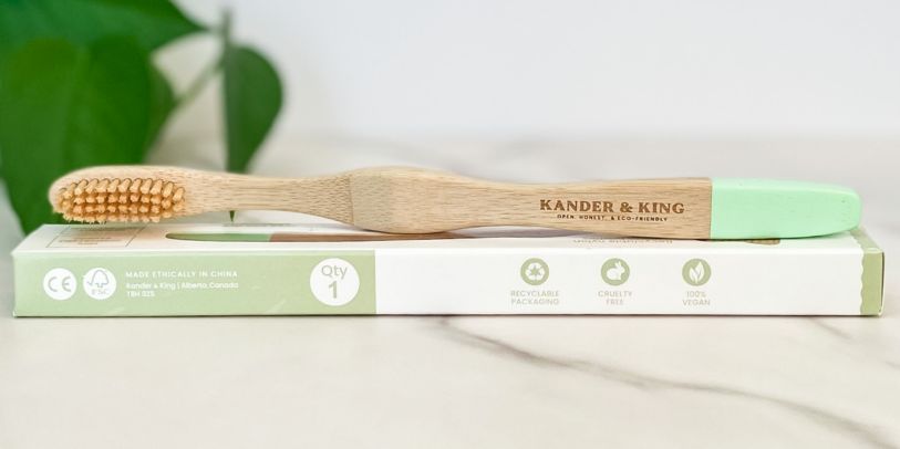 Bamboo toothbrush laying on it's side on top of it's packaging