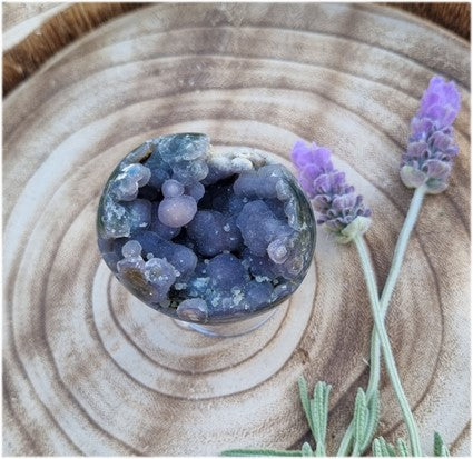Grape agate egg next to lavender on a woodblock