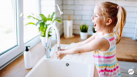 Girl washing hands in sink