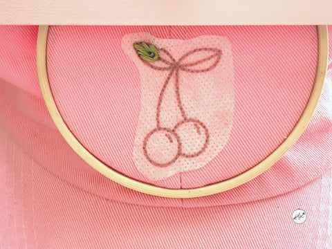 Hand embroidering cherries onto a hat using stick and stitch patterns from Haley Hamilton Art