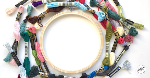 An embroidery hoop surrounded by six-strand embroidery floss 