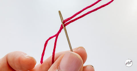 Threading an embroidery needle with pink six-strand embroidery floss