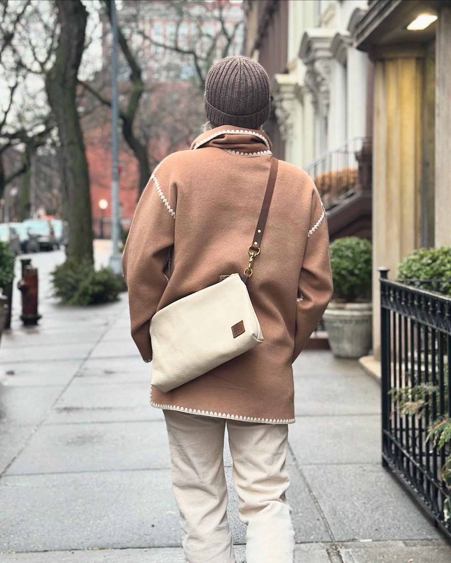 Women on a walk wearing a white leather crossbody bag
