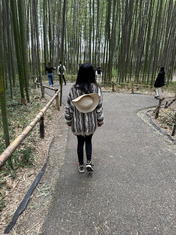 Annie walking in the Bamboo Forest in Japan. Annie is facing away from the camera and walking.