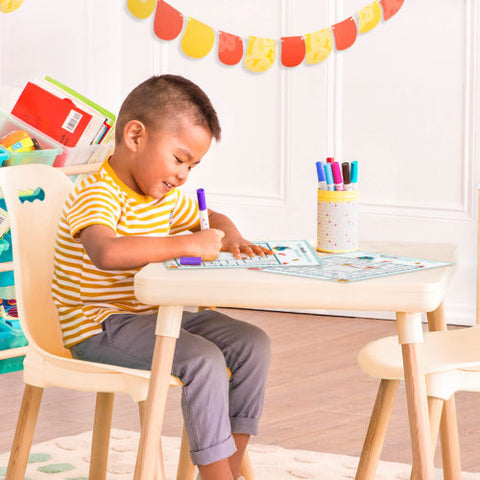 Asian boy drawing with markers on a small table and chair