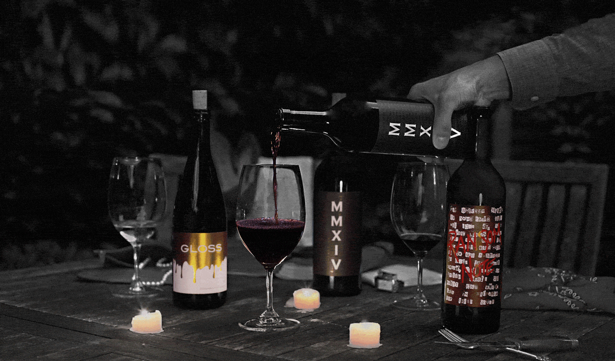 an animated gif of candles flickering around a still image of wine Foundation Cellars' MMXV Cabernet  wine being poured at night on a picnic table.