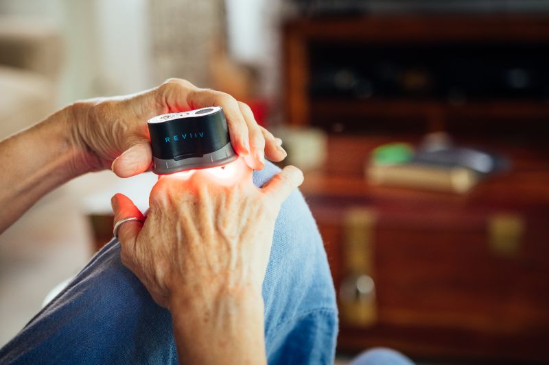 Woman holding red light therapy device on her hands