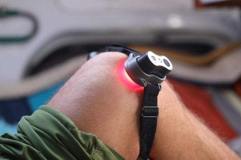 Man wearing red light therapy device on his knee