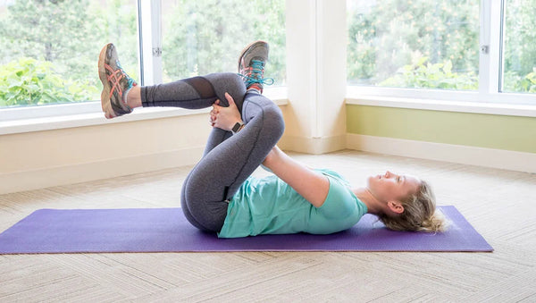 An image of a woman doing piriformis stretch, one of the exercises for lower back pain.