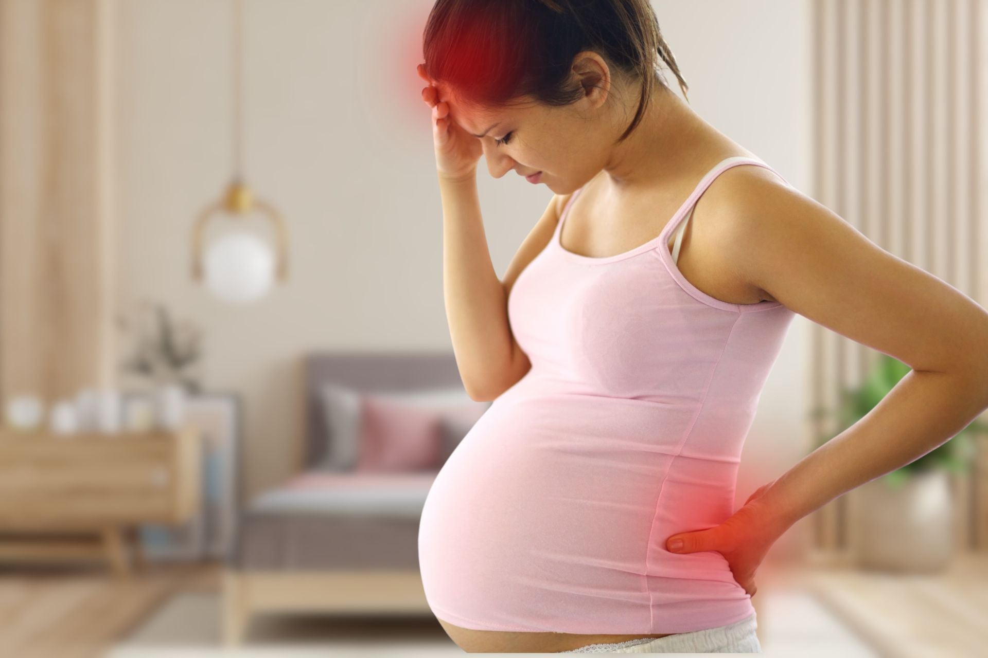 An image of a pregnant woman experiencing headach and lower back pain.