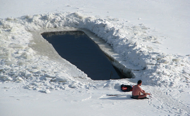 man seated next to an ice hole