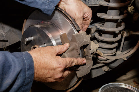 man replacing a brake caliper on a car