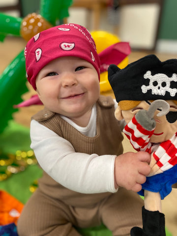 baby with red bandana and a pirate toy