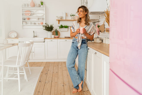 Pretty woman enjoying cozy morning on her stylish kitchen while drinking hot tea.