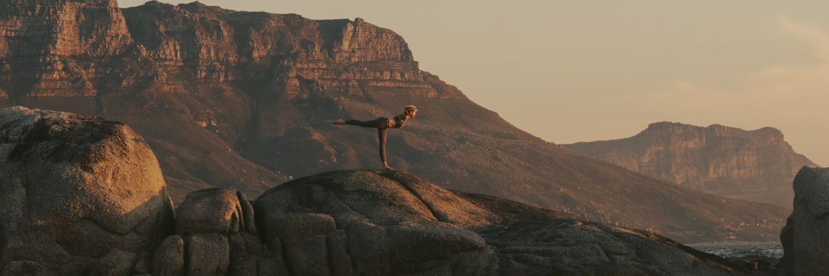 a girl doing yoga on top of a rocky mountain