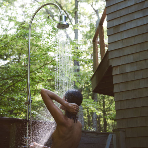 woman taking a shower outside surrounded by nature