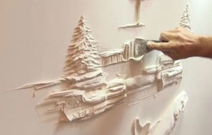 man making relief carvings of trees out of plaster on the wall