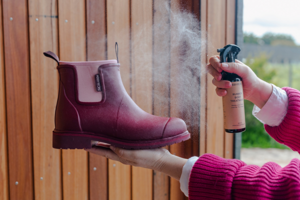 Person spraying a Beetroot Boot with Care Kit Boot Treatment Spray