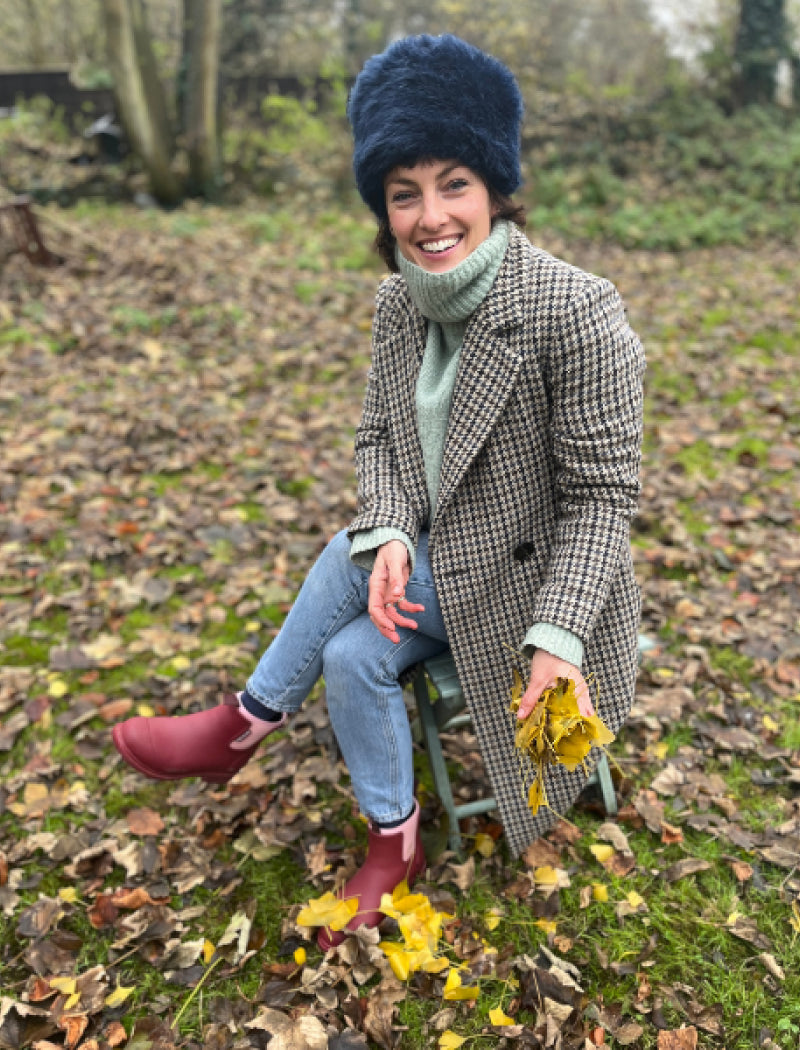 lottie delamain wearing merry boots and a coat in the garden