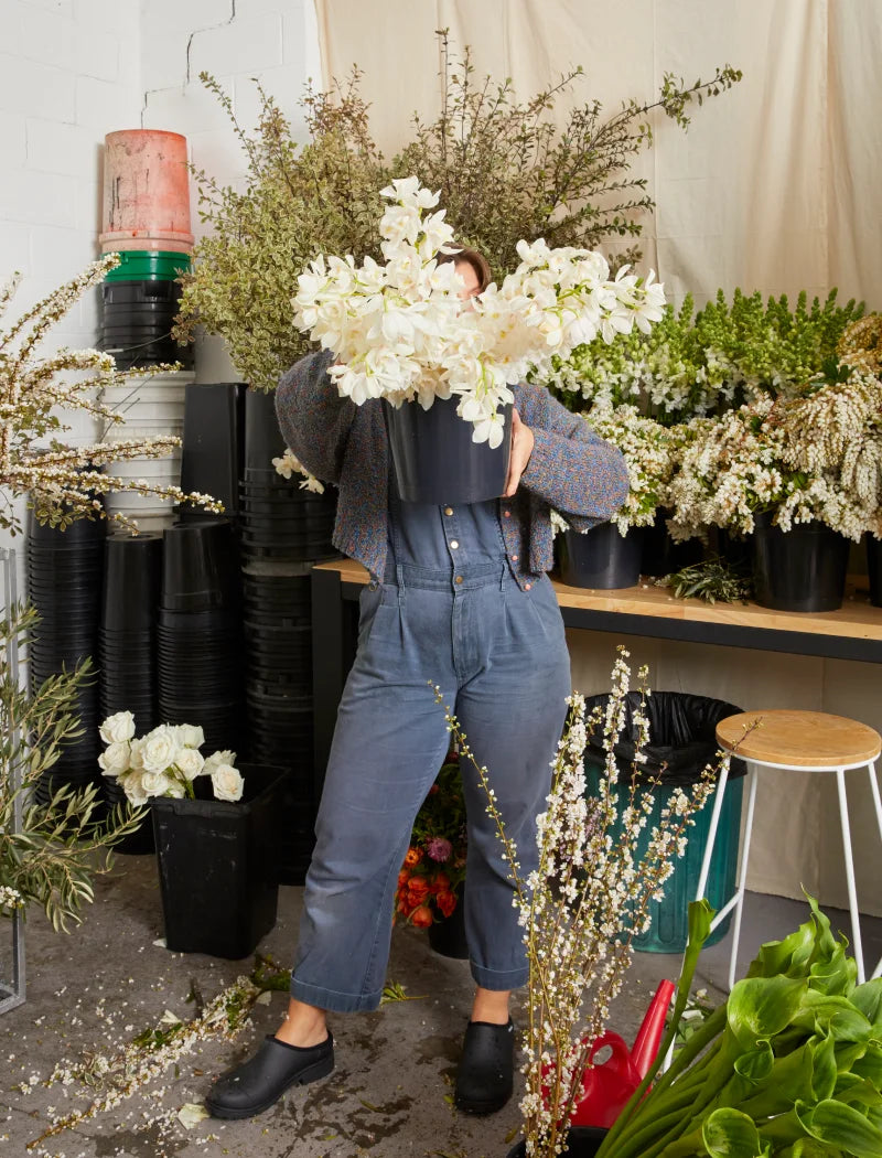 person wearing black clogs holding flowers
