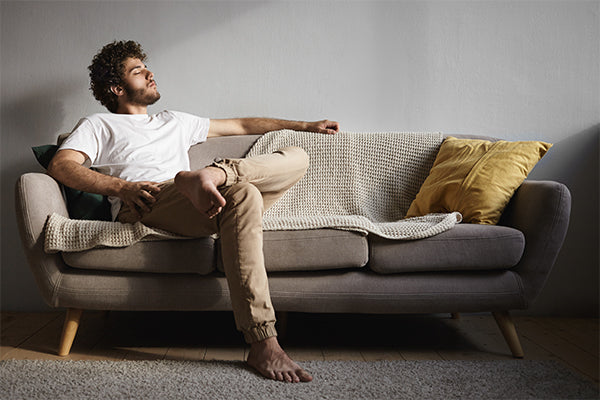 picture-stylish-handsome-young-guy-with-fuzzy-beard-voluminous-hairdo-bare-feet-keeping-eyes-closed-falling-asleep-listening-classical-music-enjoying-leisure-time-sitting-couch