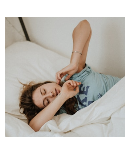 Woman sleeping peacefully in bed with white linens.