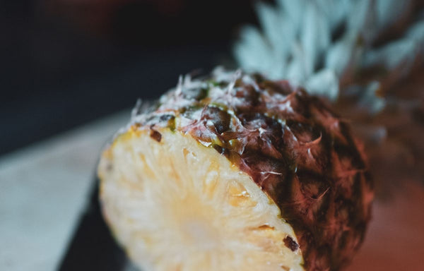 A pineapple that has been cut in half and is sitting on a hard surface